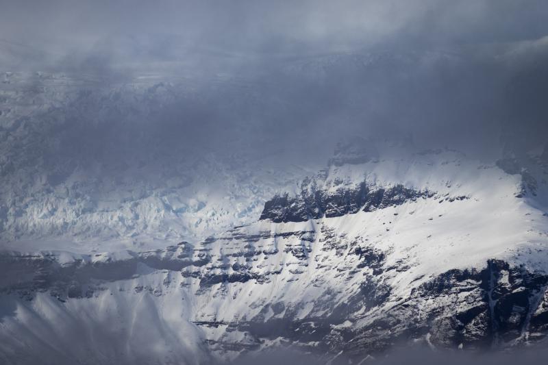 Snow-covered mountain ridges partly veiled in cloud and mist